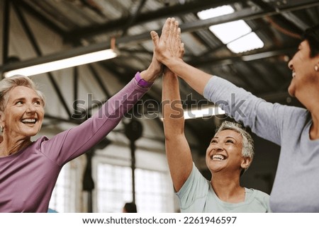 Teamwork, fitness and high five of senior women in gym celebrating workout goals. Sports targets, celebrate and group of friends with hands together for success, motivation and exercise achievements. Royalty-Free Stock Photo #2261946597