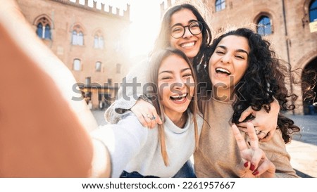 Three young women taking selfie picture with smart mobile phone on city street - Happy beautiful female friends smiling at camera outdoors -  Life style concept with cheerful girls enjoying vacation 