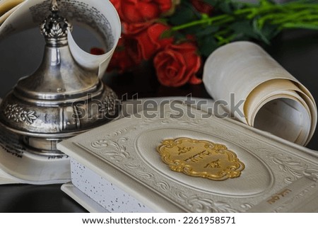 Siddur [Jewish prayer book], scroll [Torah, Megillah] and flowers in the background Royalty-Free Stock Photo #2261958571