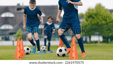 Boys on soccer football training. Young players dribble ball between training cones. Soccer summer training camp. Players on football practice session Royalty-Free Stock Photo #2261970575