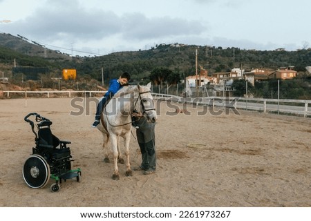 Child with disabilities hugging his equine therapy instructor. Royalty-Free Stock Photo #2261973267