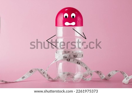 Water bottle are represent human body with cartoon drawing shocked face to with measuring tape on waist to present fat, cellulite and overweight 
