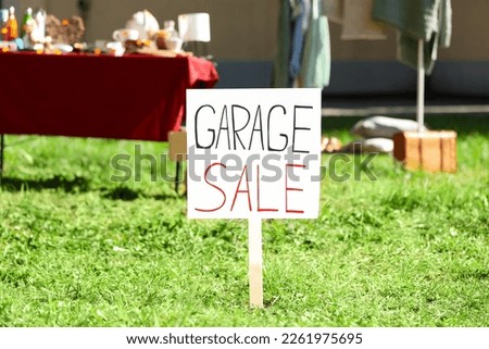 Sign Garage sale written on cardboard in yard