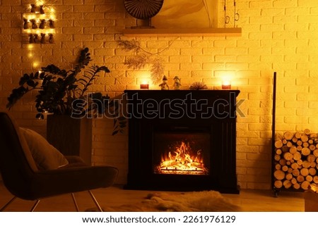Stylish fireplace with Christmas decor and accessories in room. Interior design