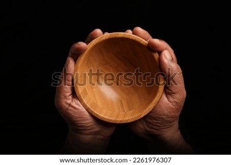 Asian dark skin top view two hand finger holding empty wooden bowl on black background 
