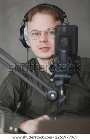 portrait of man in studio is recording podcast, audio content of interview on radio. Caucasian male speaks into microphone for voice recording or advertising. working online on internet, discussing