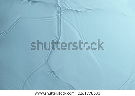 Water ripples on blue background. Transparent liquid splash from top angle.
