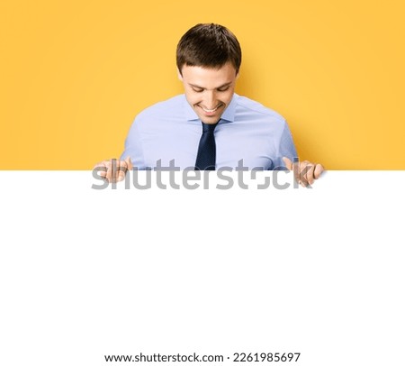 Portrait image of business man professional bank manager in confident cloth. Businessman stand behind hang over, look at empty white banner signboard with copy space. Isolate orange yellow background