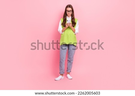 Full length photo of nice cheerful girl straight hairstyle dressed green vest typing email on phone isolated on pink color background