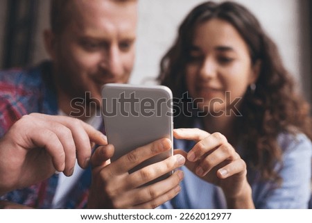 Blurred male and female bloggers using digital cellphone application for online chatting and messaging, selective frontage focus on modern smartphone technology for web social networking on leisure