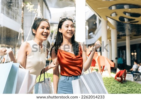 Asian young two woman shopping goods outdoors in department store. Beautiful female friend holding shopping bags then walk together with happiness enjoy purchasing in department store or shopping mall