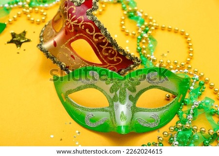 Carnival masks with confetti and beads on yellow background