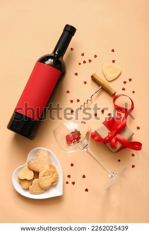 Composition with bottle of wine, glass, gift box and cookies on color background. Valentines Day celebration