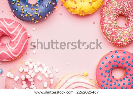 Frame made of different donuts on pink background, closeup