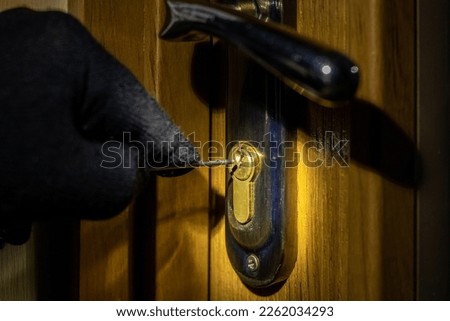 The thief tries to open the lock in the door with a special key Royalty-Free Stock Photo #2262034293