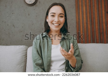 Web cam view head shot close up young woman wear casual clothes record get video call talk use pc laptop sits on grey sofa couch stay at home hotel flat rest relax spend free spare time in living room Royalty-Free Stock Photo #2262036087