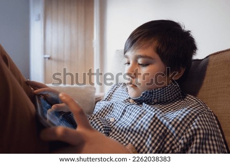 Education concept,School Kid holding tablet reading E-book for homework,Portrait happy Child playing game online on internet with friends,Young boy watching cartoon on digital pad,Kid sitting on sofa