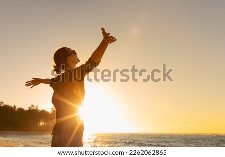 Young woman facing ocean sunset  rejoices, laughs, smiles looking up to the sky, enjoys life and summer, nature, happiness.	