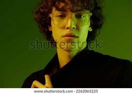 Man portrait in glasses fashion and style emotion model poses, hipster teen lifestyle, portrait green background mixed neon light, copy space