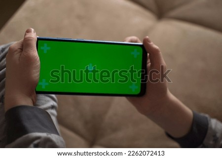 A child is using a phone with a chroma key screen mockup.