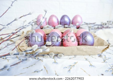 Easter eggs and willow branches on light background
