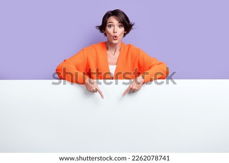 Photo of young funky pouted lips surprised woman directing fingers empty space paper banner cheap clothes isolated on violet color background