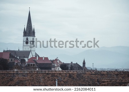Sibiu Lutheran Cathedral - a beautiful view of the ornate white tower and rooftop, and the clock. Taken on a moody day with grey skies. 