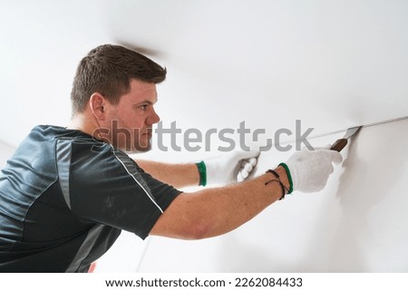 Contractor worker streching a stretch ceiling. Renovation and construction services Royalty-Free Stock Photo #2262084433