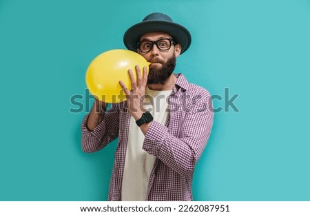 Portrait of a funny hipster guy inflating a balloon. Happy birthday concept, celebration, party. Crazy emotions. Discounts, sales, seasonal sales. Colorful summer concept.