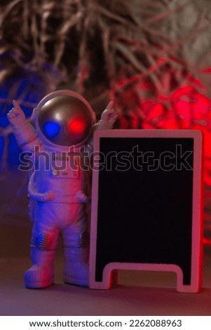 Plastic toy figure astronaut on with red and blue light Black board with Copy space for your text. Concept of out of earth travel, private spaceman commercial flights. Space missions 