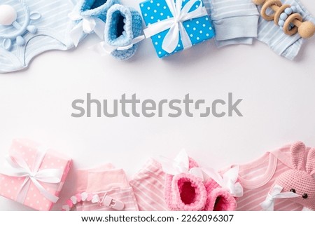 Gender reveal party concept. Top view photo of pink and blue infant clothes shirts pants knitted booties gift boxes bunny rattle toy and teether chain on isolated white background with copyspace