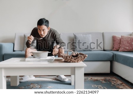 Lonely Asian man having a meal alone in his home. Royalty-Free Stock Photo #2262134097