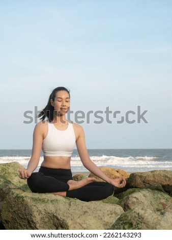 Beautiful asian woman practicing yoga on the beach. Healthy active lifestyle concept. Zen yoga meditation practice in nature.