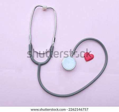 flat lay a red heart gray stethoscope isolate on a pink doctor table.minimalist trend. love and valentines day concept