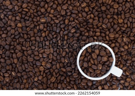 Top view white cup on coffee beans medium roast background.