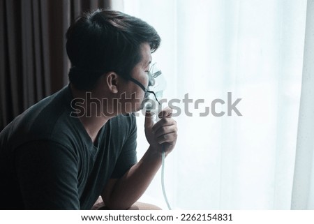 Panoramic shot of asthmatic man using inhaler with spacer. Fat man using asthma inhaler while sitting at home due to allergy. Asia man using spray asthma. Royalty-Free Stock Photo #2262154831