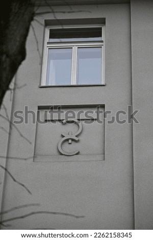 a fragment of the building facade with a window and a modest element of decor below the window