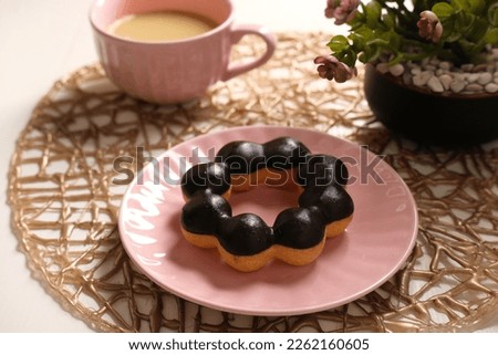 sweet donut on pink ceramic plate  with a cup of milk tea. 