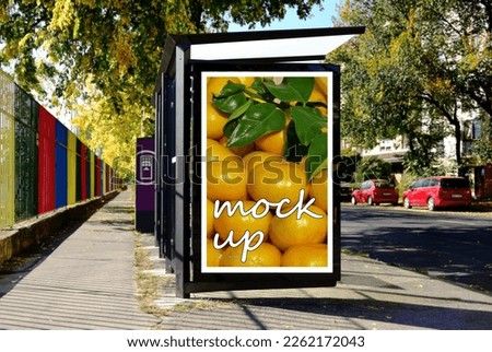 glass bus shelter at busstop. lightbox sign. sample poster. aluminum structure. urban setting. city street background. asphalt road. template ad. commercial space with street background for mockup