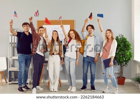 Young people who take part in university exchange program meet and make friends of different nationalities. Happy cheerful joyful international students standing together, holding up flags and smiling Royalty-Free Stock Photo #2262184663