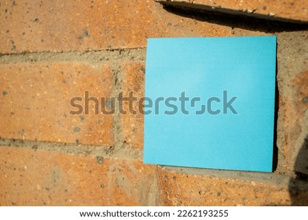 a blue square paper note resting on brickwork with empty free space for template or blank copy area