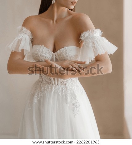 Trendy classic wedding dress with cleavage and wide short sleeves decorated with floral lace. Bride in the shoulderless white wedding dress with deep neckline and fancy sleeves Royalty-Free Stock Photo #2262201965