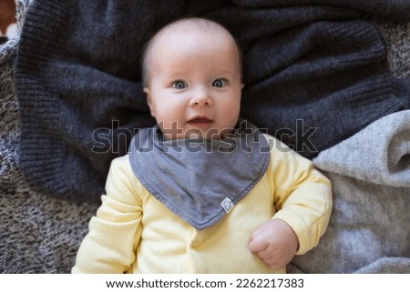 Happy caucasian baby girl five months old lying on knitted blanket. Colors of the year 2021 ultimate gray and illuminating