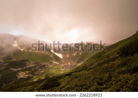 Mountain lake with thick mist landscape photo. Beautiful nature scenery photography with blurred background. Ambient light. High quality picture for wallpaper, travel blog, magazine, article
