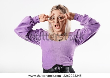 Happy woman wearing ribbed blouse standing isolated over white background doing peace symbol with fingers over face, smiling cheerful showing victory. Wow face! Very happy about what hears.