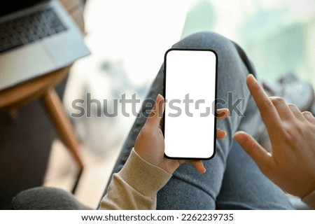 Close-up image of a woman in jeans relaxes sitting in the cafe and using her smartphone. smartphone white screen mockup for display your graphic banner. Royalty-Free Stock Photo #2262239735
