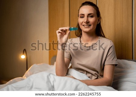 An attractive woman uses a multifunctional trainer at night, before going to bed. They help to align the growing teeth and correct the bite. Corrects the position of the tongue.  Royalty-Free Stock Photo #2262245755