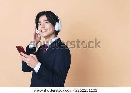 Young Asian man listening to music with smartphone and headphones. Music distribution service. Streaming audio.