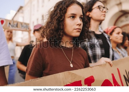 Diverse young people protesting against war and violence in the streets. Group of youth activists holding anti-war banners during a peace and human rights demonstration. Royalty-Free Stock Photo #2262253063