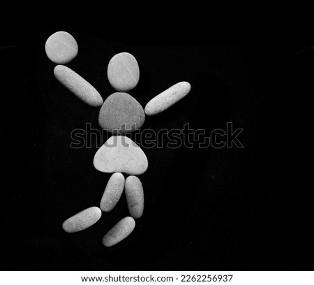 Jumping  Man Silhouette with Ball for Volley Sport. one single human figure jumping with ball isolated on black background. Male or female symbol made from many pebbles. stones in the form of woman